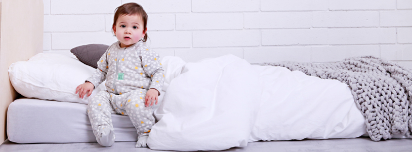 Toddler sitting on big bed mattress on floor