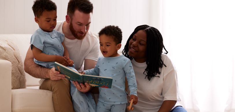 Parents reading to her toddler daughter whilst travelling to replicate their bedtime wind-down routine