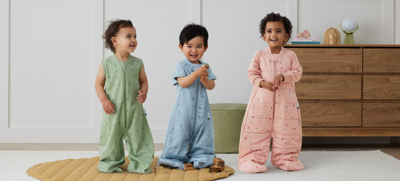 3 toddlers standing wearing sleep suit sacks